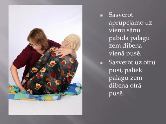 Sasverot aprūpējamo uz vienu sānu pabīda palagu zem dibena vienā pusē.